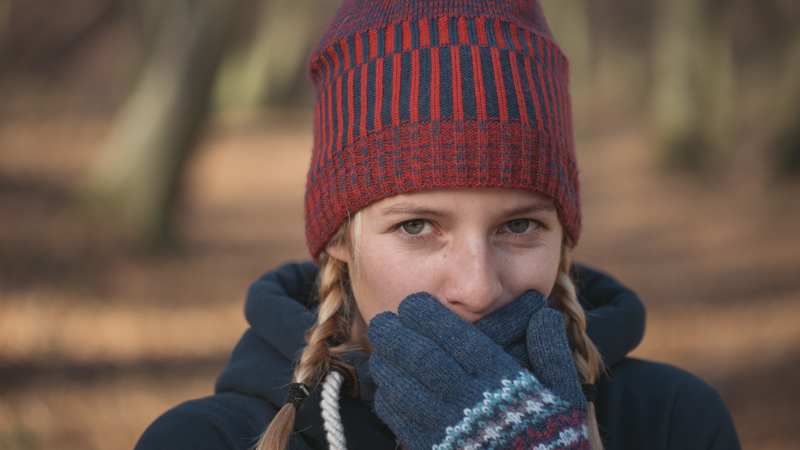 mulher com gorro e luvas a proteger cara do frio